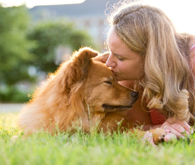 woman kissing dog on forehead